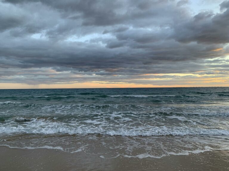 A tranquil evening view of Calp beach with waves and a colorful sky.