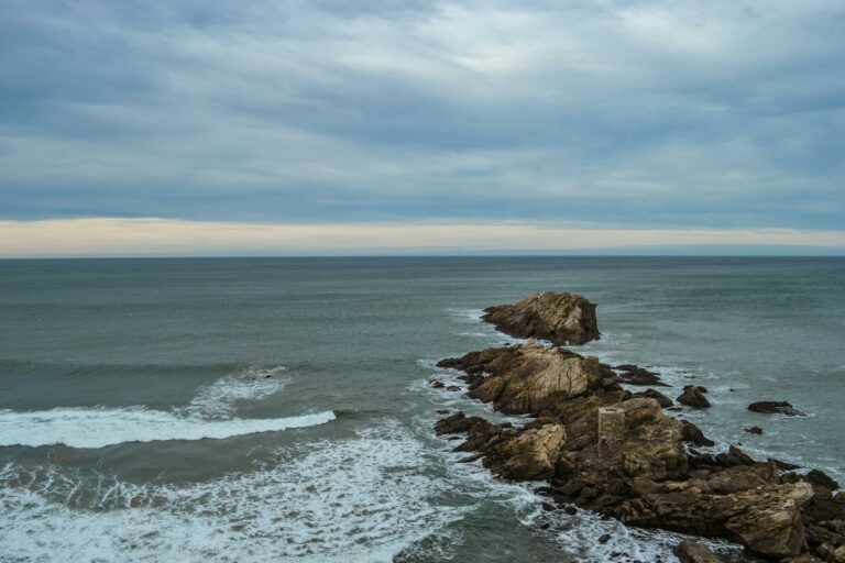 Capture of rugged rocks and waves at Zarautz beach on a cloudy day.
